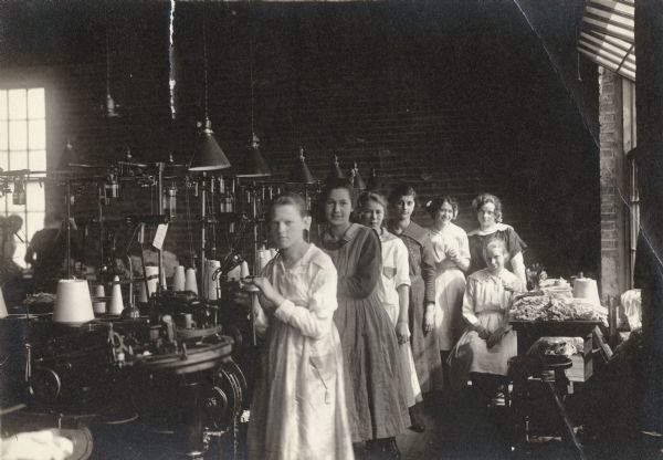 Young women pose in a hosiery factory where they are employed.
