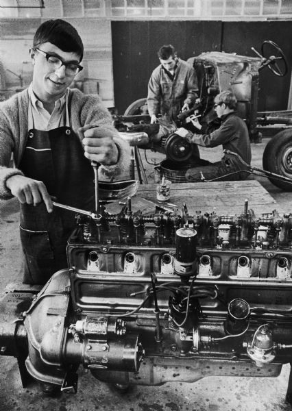 Charles Richter (foreground) works on an engine as William Pritzl (left, background) and Timothy Hendricks work on a chassis in a high school vocational car repair class.