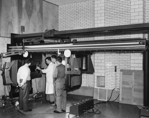 Three students listen to an instructor talk about a lithographic camera in a graphic arts class at the Milwaukee Institute of Technology.