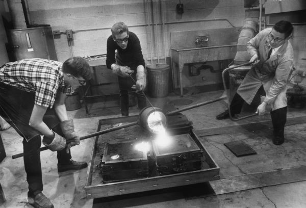 Instructor George Finco (right) teaches skill and safety to students Michael Edler (left) and Jeff Zinuticz in the Custer High School foundry.
