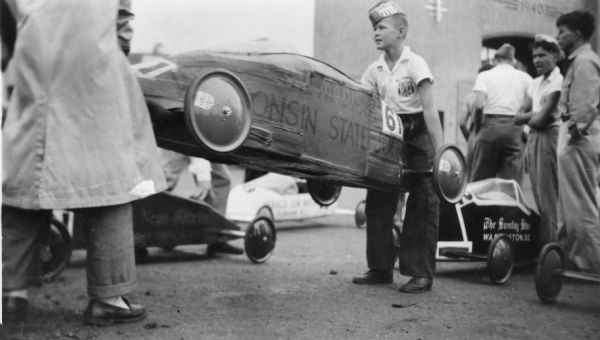 Paul R. Anderson of DeForest, Wisconsin won the 1946 Madison Soap Box Derby and went on to race at the All-American Soap Box Derby in Akron, Ohio.  Here he is unloading his car, repainted with "Wisconsin State Journal," for the Akron race.