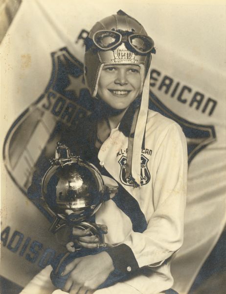 Paul R. Anderson of DeForest, Wisconsin, winner of the 1946 Madison Soap Box Derby, who went on to race at the All-American Soap Box Derby in Akron, Ohio.  He is shown holding his Madison trophy and wearing the shirt, helmet, and goggles given to him when he competed in Akron.  He carried the flag he is posed in front of during the Parade of Champions at Akron.