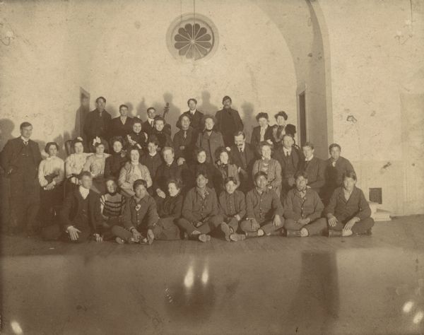 Group portrait, perhaps consisting of students and faculty at Hayward Indian School. One man in the back row holds a cello.