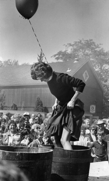 Patricia Mallach of Waukesha demonstrating grape stomping to a crowd of onlookers during the Wine and Harvest Festival. She has a balloon tied around her neck.