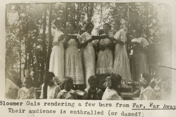 Group of women known as The Bloomer Gals singing at a Labor Day picnic. Several children are seated in the foreground. The women are identified as Ida Rathke, Helen Gruner, Viola Scheel, Mabel Broitzmann, Margaret Broitzmann, and Martha Gruner.
