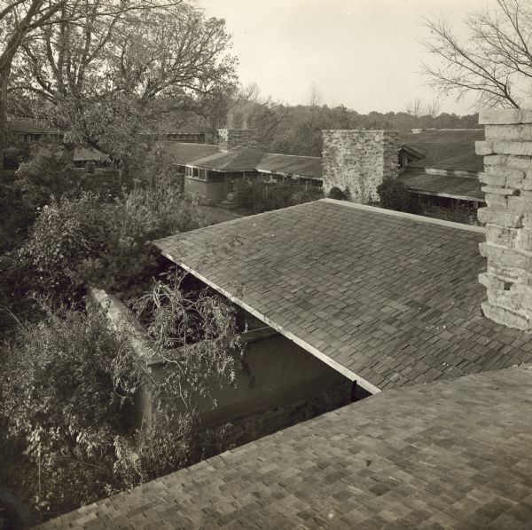 View of Taliesin courtyard from the roof of the bedroom wing of the residence.  In the foreground is the roof of the porte-cochere. The workroom chimney and the apartment are visible at the back of the courtyard.