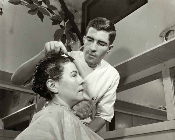 A hairstylist applying hair color to a woman's hair.