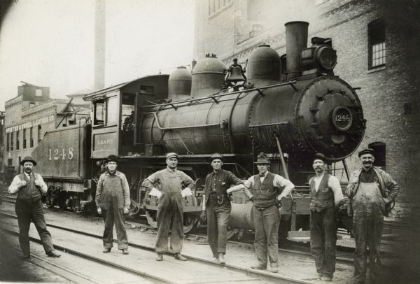 Chicago, Milwaukee & St. Paul Railway locomotive engine no. 1248, class I5, built by the company's shop in 1912. From left to right are waymaster Harvey Giskie, carman Joseph Luedtke, fireman Herbert Apler, switchman James Heney, switchman Jesse Warner, switchman and foreman crew August Mau, and engineer Omro B. Mills.
