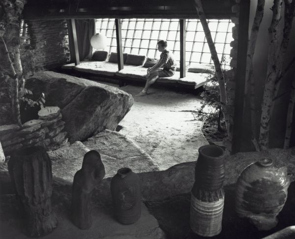 Interior of room at House on the Rock. A young man is sitting on a bench near the window.