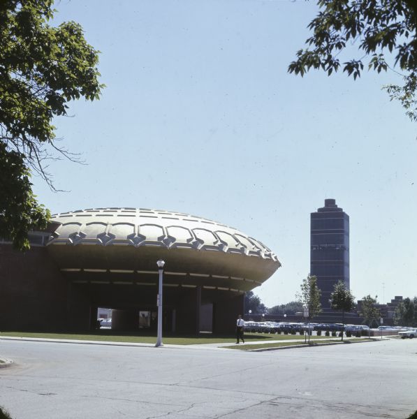 View of the Golden Rondelle with the Johnson Wax Research Tower in the background taken from the northeast corner of Franklin and 14th Streets.There is a parking lot full of cars behind the structure.