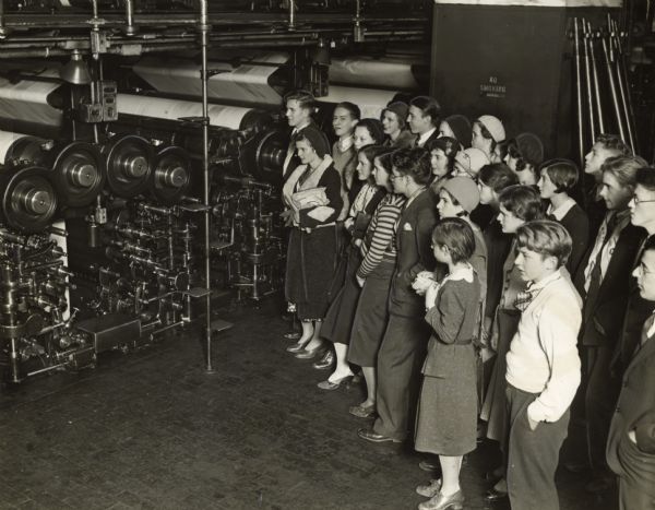 Slightly elevated view of a group of Oconomowoc High School students on a tour at the "Milwaukee Journal." They are viewing the newspaper's presses in operation.