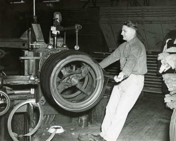 Tire builder Arnold Brandt rolls the tread onto a heavy service truck tire.