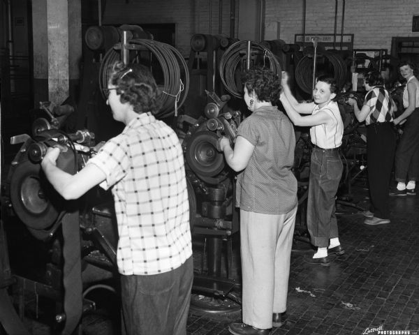 Women work in a row on machinery building tires.