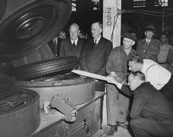 The first tire to be cured in the Gillette Tire Plant is removed from the mold. From left to right are F.B. Davis Jr. (Chairman of the United States Rubber Company's Board of Directors), factory manager Howard O. Hutchens, curing room employee Luvig Landsverk, U.S. Rubber Company President Herbert E. Smith, and J.W. McGovern, General Manager of the tire division.