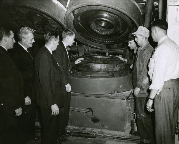 The first raw tire is placed in a mold at Gillette Tire Plant. From left to right are R.L. Chatterson, Julius Berkley, A.B. Smith, M.O. Wick, J.W. Harry Kunz, R.F. McSorley, and F.I. Hagman.
