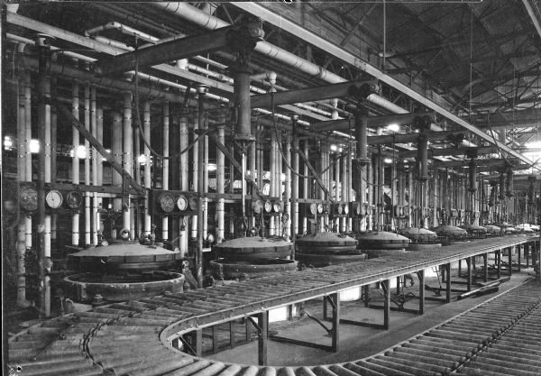 Interior view of a Uniroyal factory showing tire molds alongside a conveyor belt.