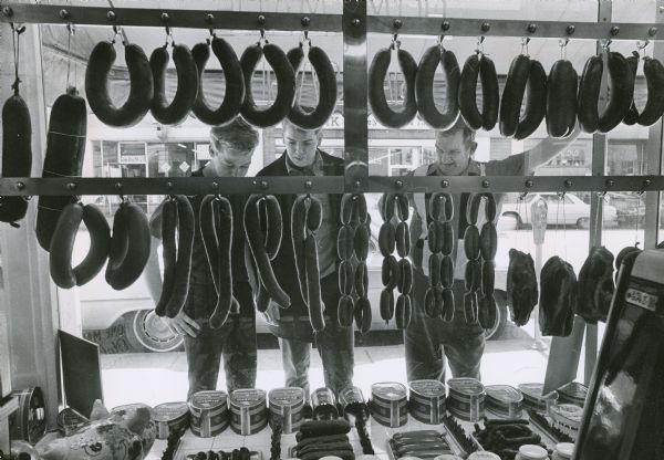Richard Bublitz, William Mackowiak and Edward McPhetridge looking through a window at a sausage display in a delicatessen owned by Charles E. (Bud) Gillett and his wife Cassie at 728 W. Mitchell Street. At the time the photograph was taken, the deli had been in business for forty years.