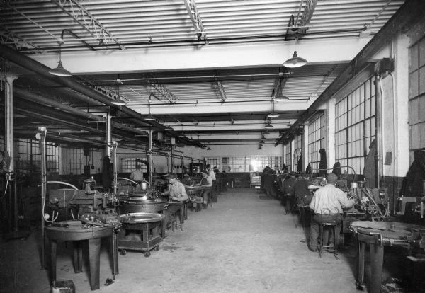 Men sit on chairs while working on tire molds at Uniroyal.