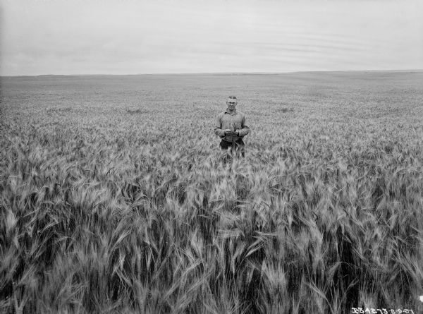 Man standing in the middle of a field of wheat.