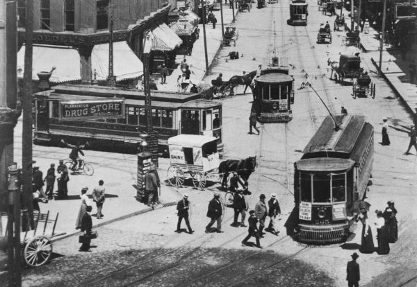 Elevated view of scene at the corner of Grand (Avenue?) and West Water Street, now Plankinton and Wisconsin Avenues. Several streetcars are in the streets as well as horse-drawn wagons and pedestrians.