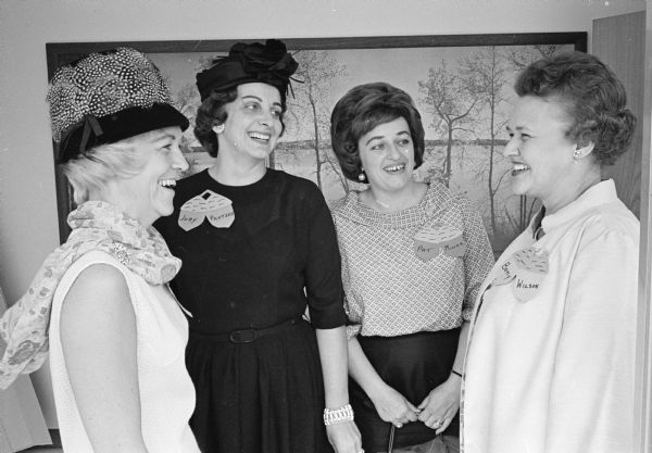 Four members of the Who's New Club chat together at the Who's New fall luncheon. Each woman is wearing an acorn-shaped name tag.