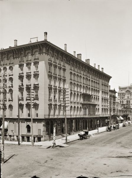 Elevated view of Newhall House. A number of horse-drawn vehicles are parked along the curb.