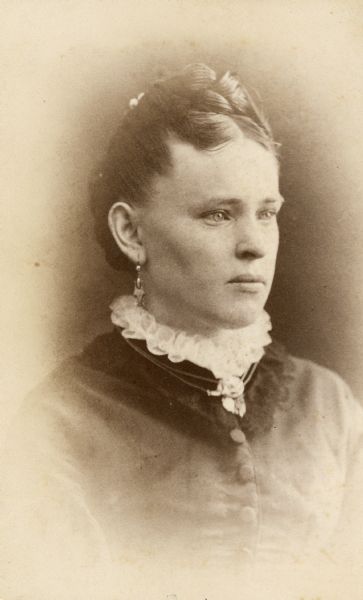 Vignetted quarter-length portrait of Kunigunde (Dorn) Willms (1857-1941) of Milwaukee, Wisconsin. Her hair is pulled back, and she wears earrings, a white lacy collar under a jacket, and a necklace.