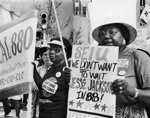 Women hold signs at an ACORN rally. One woman's sign touts "Jesse Jackson in '88!".