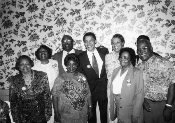 Barack Obama (in a suit and necktie) poses with ACORN members. They are all wearing ACORN and Obama buttons.