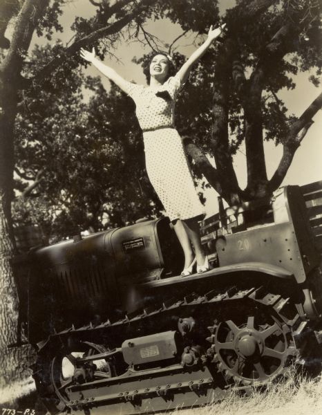 Actress Steffi Duna stands on the International T-20 TracTracTor (crawler tractor) used in the motion picture <i>Escape by Night</i>.