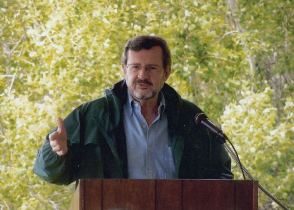 Informal portrait of Wisconsin Congressman David R. Obey standing at an outdoor podium at the Ice Age Trail Visitors Center. Trees fill the background.