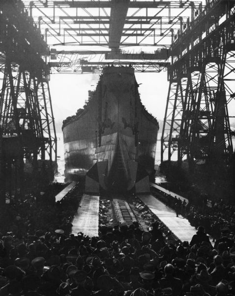 View of the battleship U.S.S. <i>Wisconsin</i> launching. A large group of spectators is gathered in the foreground.