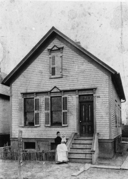 Woman holding child standing in front of the home at 1554 W. Windlake Avenue. There is a small garden in the front yard.