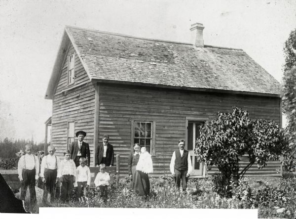 Ten members of the Martin Schulist family standing in front of their frame home.