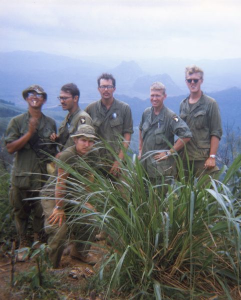 Standing left to right: Patrick Bailey, Lt. Donald Speet, Steve Commo (Doc), Capt. Carl Jensen, Donald Thies; in front: Buford Byers on a hilltop overlooking firebase [Vandegrif](?) with Rockpile and Razor Back in background. The men were part of Co. B 2nd 506th COIST airmobile.