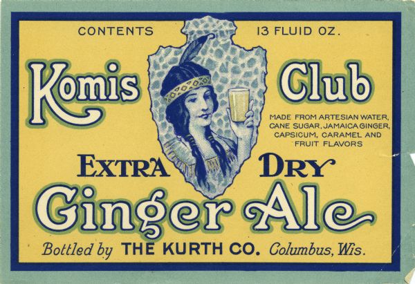 Komis Club Extra Dry Ginger Ale label. The label features a drawing of a Native American woman wearing a headdress with a single feather and holding a glass of ginger ale superimposed on an arrowhead. Komis Club was bottled by the Kurth Co. of Columbus, Wis.