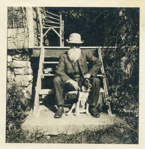 John Burroughs seated with his dog on the steps of "Slabsides," his cabin retreat.