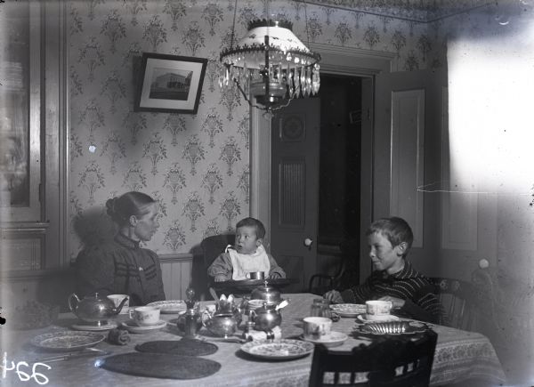 Mrs. Herbert C. Scofield, with sons Lloyd and Stanley at the dinner table.