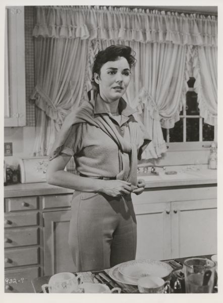 Movie still from the Twentieth Century-Fox movie "The Man in the Gray Flannel Suit," featuring Jennifer Jones (playing Betsy Rath) who is shown standing in a kitchen.
