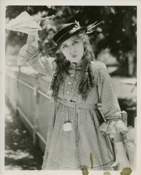 Movie still from the Artcraft movie "Rebecca of Sunnybrook Farm," featuring Mary Pickford (playing the title role) goofing off with a parasol.
