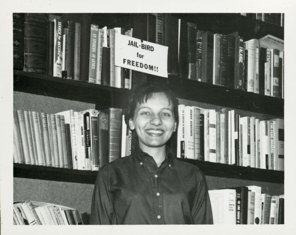 Diane Nash Bevel stands smiling beneath a small sign that reads "Jail-Bird for Freedom!".