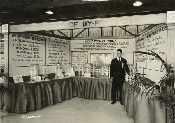 A man in a suit stands at a table in an exhibit titled "Utilization of Whey".
