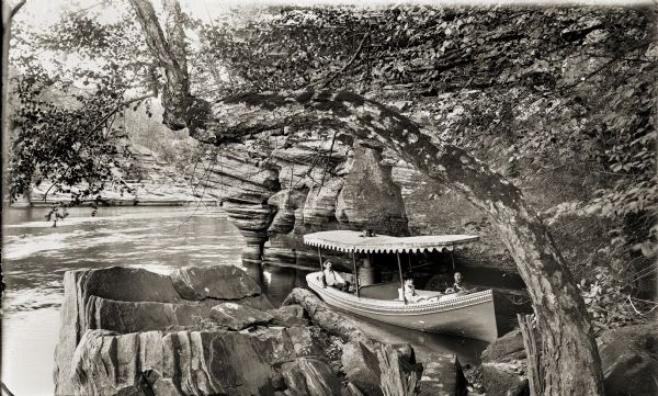 Elevated view of the doctor in a launch boat at Eagle Point. Two women are sitting in the front of the boat.