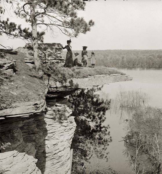 Evaline Marshall Bennett, unidentified person, Miriam Bennett, and Ruth Bennett sitting and standing on the Visor Ledge.