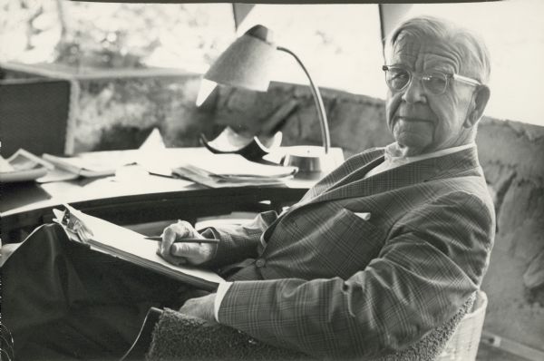 William Evjue seated at a desk.