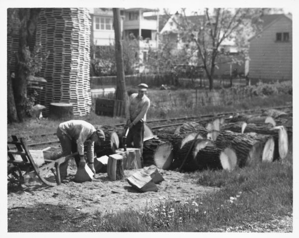 Employees of Hess Cooperage quarter log sections for barrel-making. The man standing in the middle of the image is Joe Hess.