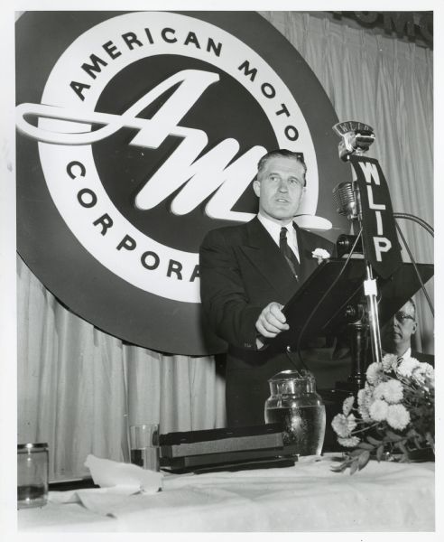 George Romney speaks at the Kenosha Chamber of Commerce Annual Dinner. Robert L. Grover is partially visible, seated next to where Romney stands.