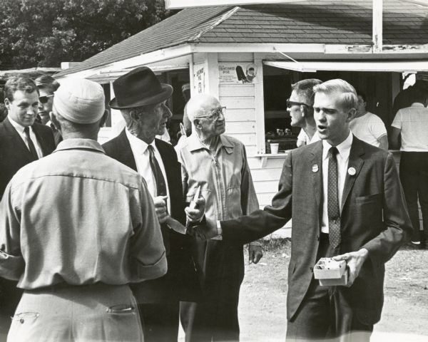 Bill Steiger (right) speaks to several men as he campaigns for congress. Dick Cheney is visible on the far left.