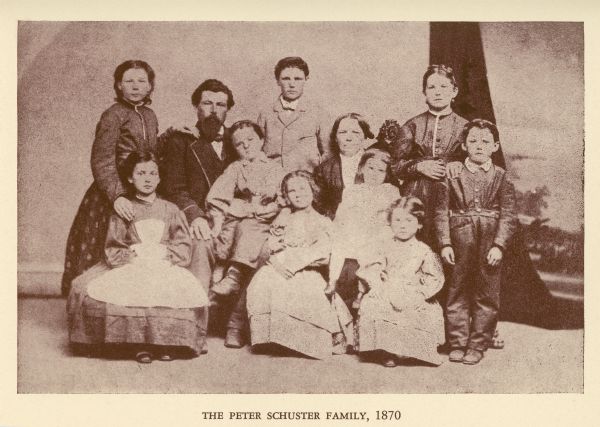 A family portrait of the Peter Schuster Family in front of a painted backdrop.
