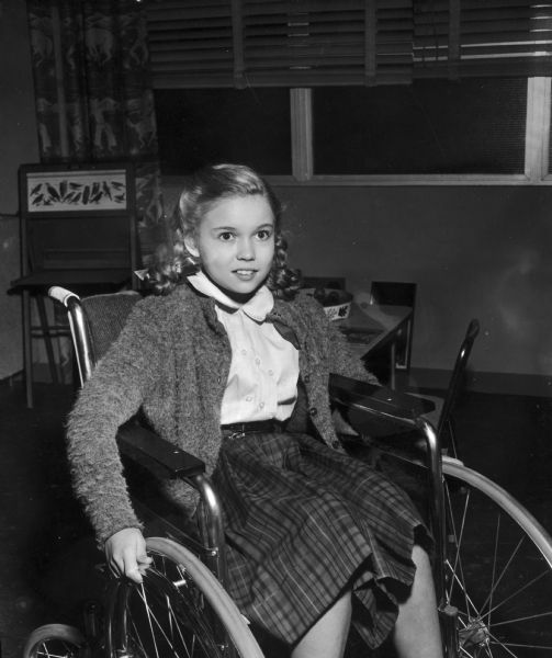 Mimi Gibson is seen in a wheelchair on the set of the television show <i>Men Into Space</i>. Her character's name is Jenny.